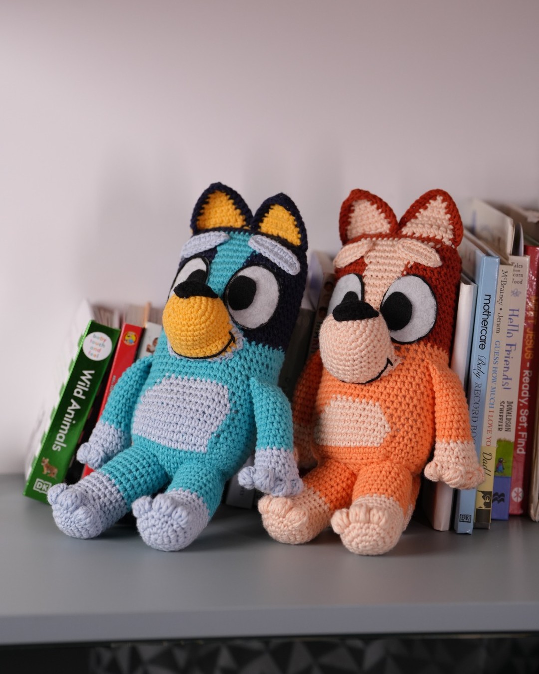 Bluey and Bingo crochet dolls on a nursery shelf